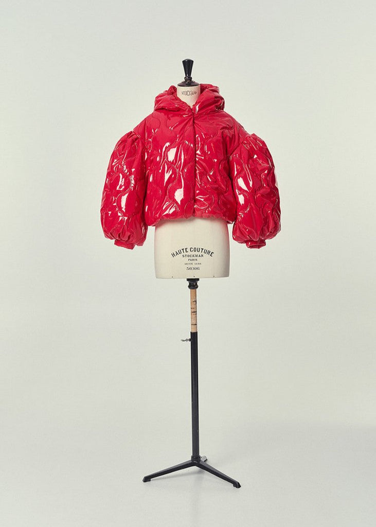 Composition: Out : 100% Polyurethane 5% Elastane 79% Polyester In: 100% Polyester Padding: 100% Polyester

Made in: Spain

Short jacket with hood and puffed balloon sleeves, made in shiny quilted red patent PU fabric. Fastens with press studs and pockets on the sides, with a fine concealed elasticated hem that adjusts to the body.