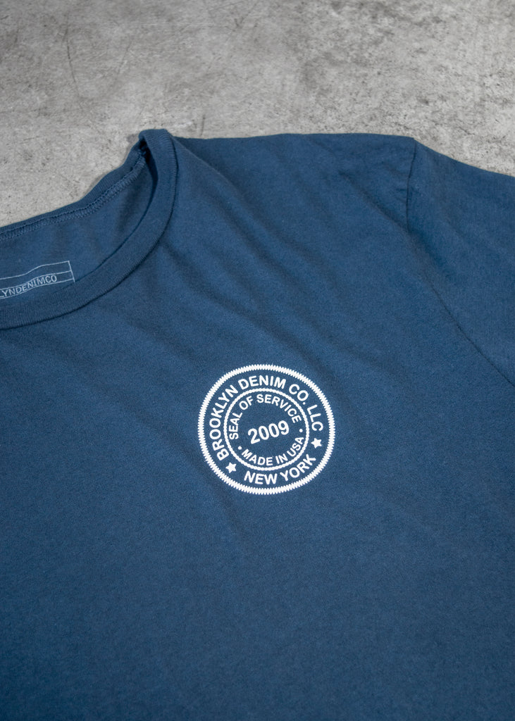 Brooklyn Denim Co. Graphic Tee. This Brooklyn Denim Co. screen printed logo seal tee is a super soft short sleeve tee with a crew neckline.

Details:

*100% organic cotton

*Pre-Shrunk

*No tag

*Made in USA